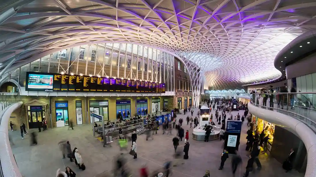 White diagrid roof and departure area inside London King’s Cross station, a major East Coast Main Line terminus.