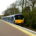 ScotRail train stopped beside a station platform with trees in the background