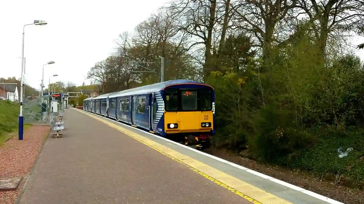ScotRail train stopped beside a station platform with trees in the background
