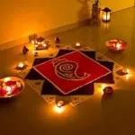 A colourful floor rangoli surrounded by lit clay diyas and brass bowls of flower petals during Diwali