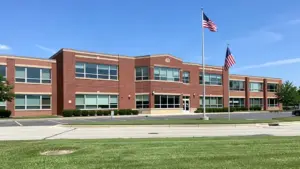 Front entrance and exterior brick facade of a public high school in suburban Michigan under daylight.