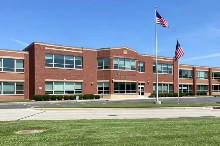 Front entrance and exterior brick facade of a public high school in suburban Michigan under daylight.