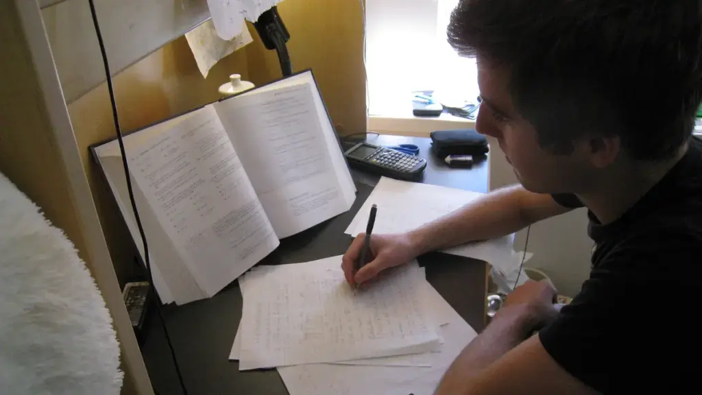 Student studying at a desk with textbooks and papers while preparing for college financial aid