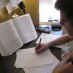 Student studying at a desk with textbooks and papers while preparing for college financial aid