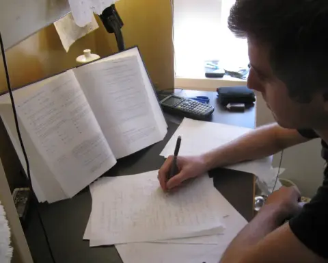 Student studying at a desk with textbooks and papers while preparing for college financial aid