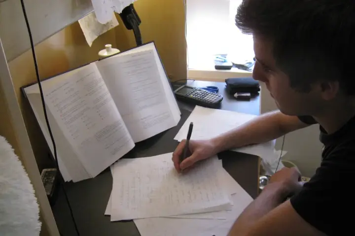 Student studying at a desk with textbooks and papers while preparing for college financial aid