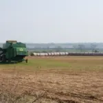 A heavy agricultural combine harvester harvesting grain crops