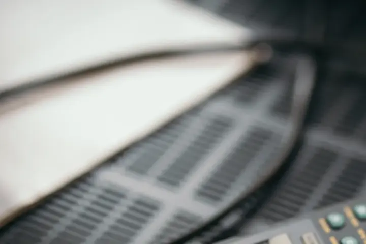 Close-up photograph of a television remote control sitting in front of a home entertainment television screen