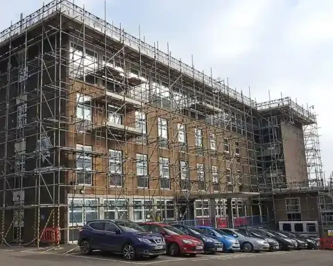 Exterior of a Suffolk Police station building with scaffolding and parked cars nearby