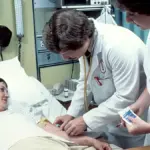 Clinician taking or preparing a blood sample from a patient in a hospital setting
