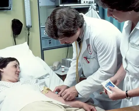 Clinician taking or preparing a blood sample from a patient in a hospital setting