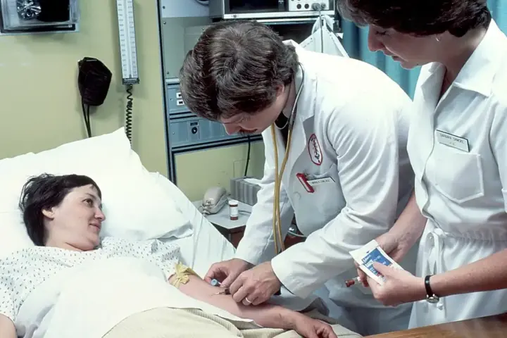 Clinician taking or preparing a blood sample from a patient in a hospital setting