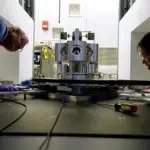 NIST researchers examining a torsion balance used to measure the gravitational constant