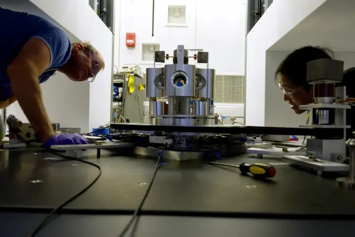 NIST researchers examining a torsion balance used to measure the gravitational constant