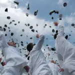 University graduates in academic regalia tossing graduation caps into the air at a commencement ceremony