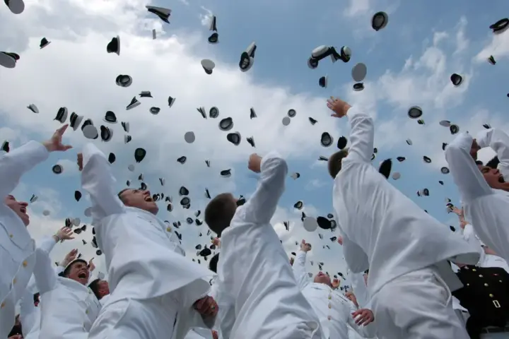 University graduates in academic regalia tossing graduation caps into the air at a commencement ceremony
