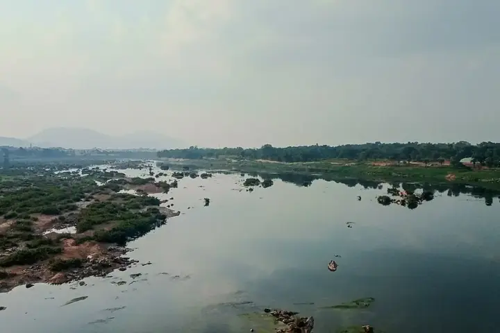 The Subarnarekha river flowing between vegetated earthen banks and rocky terrain upstream of coastal plains.