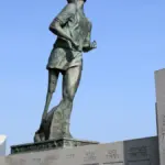 Bronze statue of Terry Fox in mid-stride on a stone pedestal overlooking Thunder Bay and the Trans-Canada Highway.
