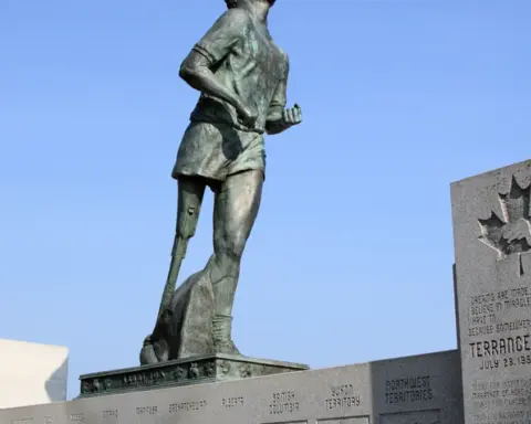 Bronze statue of Terry Fox in mid-stride on a stone pedestal overlooking Thunder Bay and the Trans-Canada Highway.