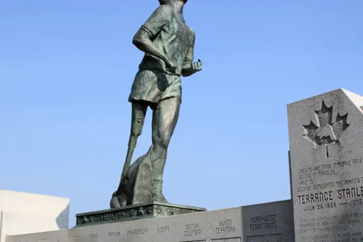 Bronze statue of Terry Fox in mid-stride on a stone pedestal overlooking Thunder Bay and the Trans-Canada Highway.
