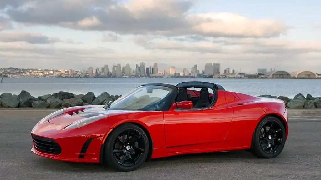 An electric sports car displayed outdoors on open pavement under direct daylight.