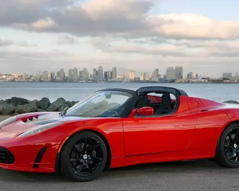 An electric sports car displayed outdoors on open pavement under direct daylight.