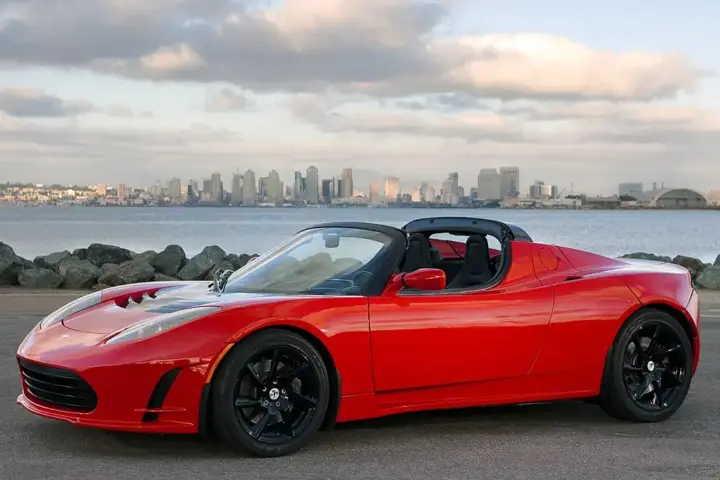 An electric sports car displayed outdoors on open pavement under direct daylight.