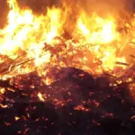 Large flames burning through wood and debris at night
