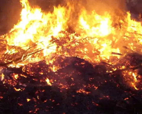 Large flames burning through wood and debris at night