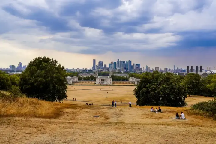 Dry ground and park lawn in Greenwich Park overlooking Canary Wharf in London.