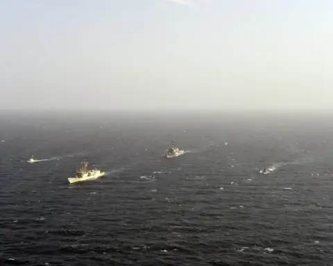 A gray naval guided-missile destroyer slicing through open ocean waters in the Persian Gulf during maritime security patrols.