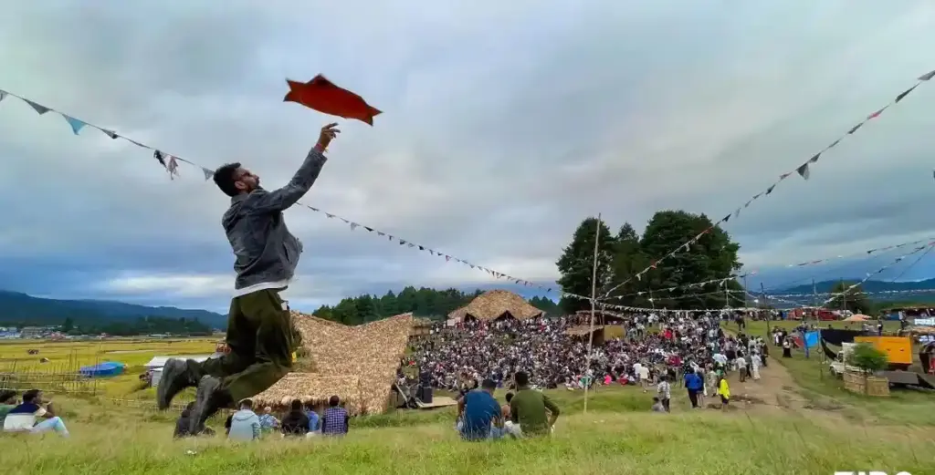 Ziro Festival crowd in an open field with bamboo structures and hills in the background