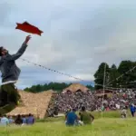 Ziro Festival crowd in an open field with bamboo structures and hills in the background