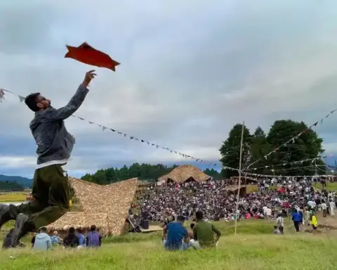 Ziro Festival crowd in an open field with bamboo structures and hills in the background