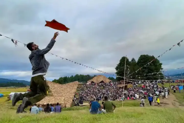 Ziro Festival crowd in an open field with bamboo structures and hills in the background