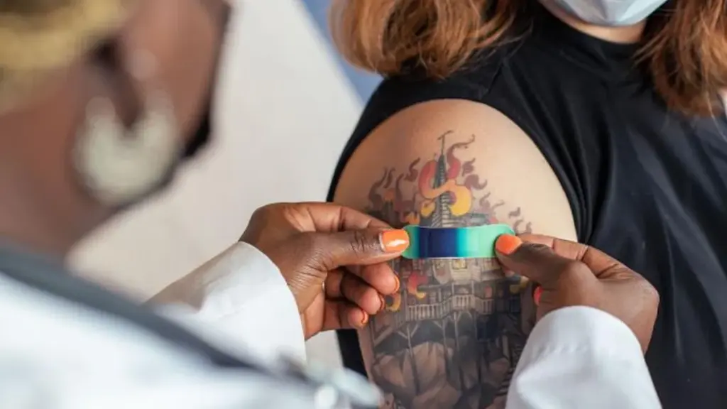 Healthcare provider placing a bandage on a patient's arm after a seasonal influenza vaccination in a clinical setting
