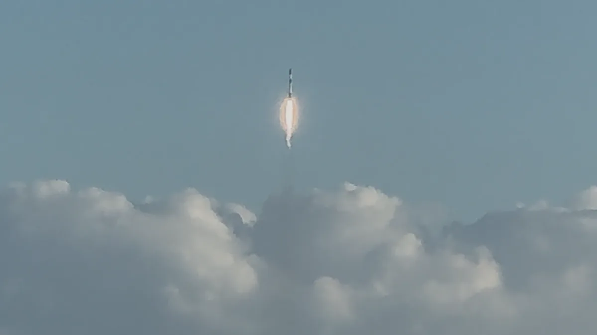Falcon 9 rocket ascending from a launch pad with a bright plume against a dark sky.