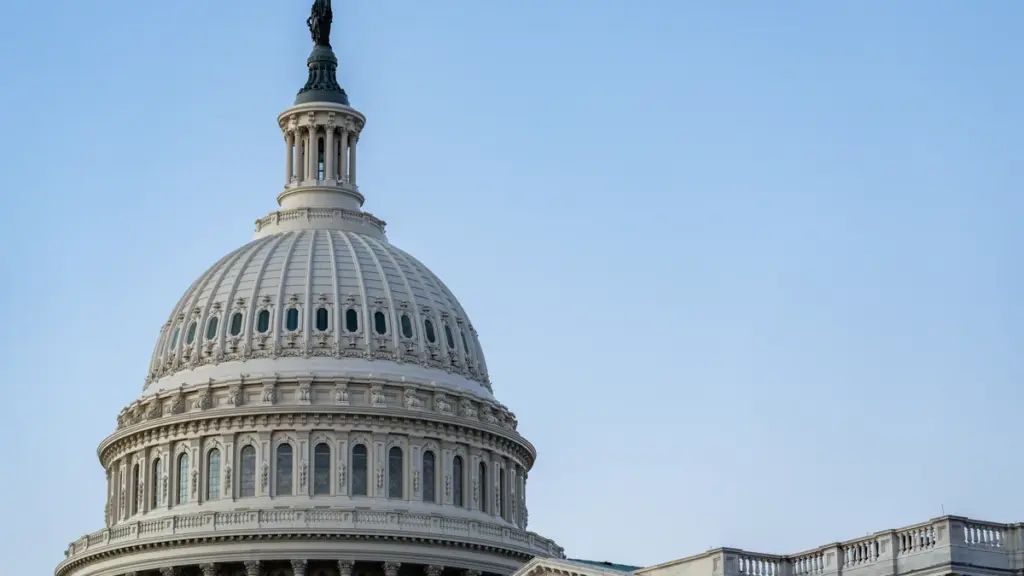 Close view of the white U.S. Capitol dome against a blue sky.