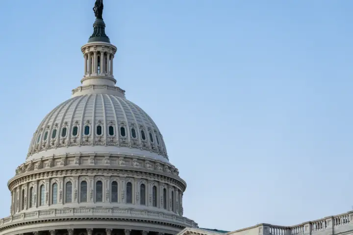 Close view of the white U.S. Capitol dome against a blue sky.