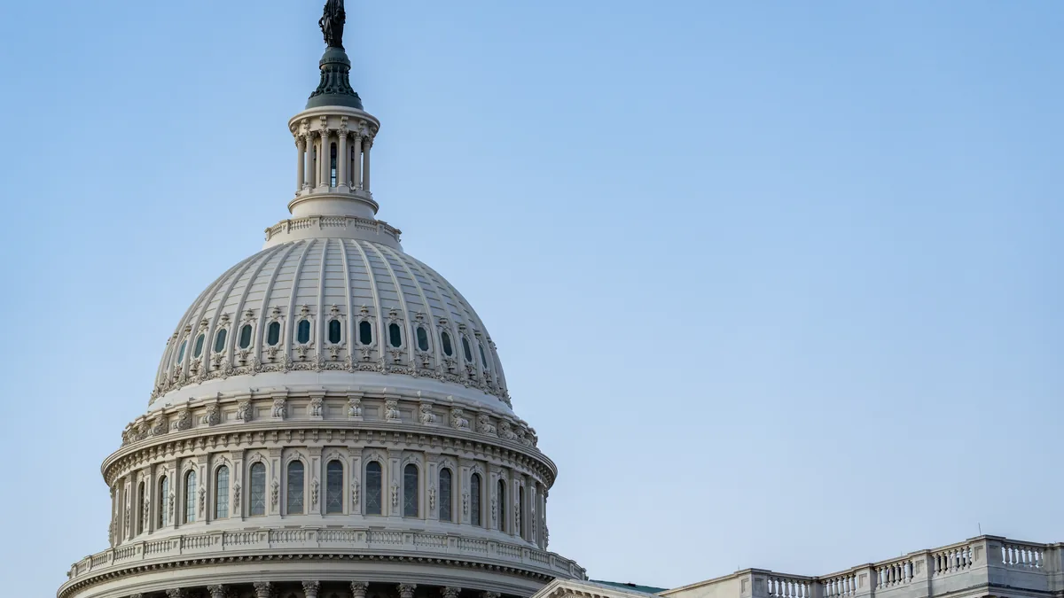 Close view of the white U.S. Capitol dome against a blue sky.
