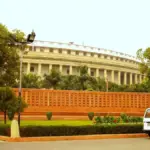 Exterior of India’s circular Parliament building in New Delhi under a blue sky.