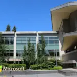 Daytime architectural photograph showing the glass facade, entrance, and landscaping of Building 92 at the Microsoft corporate campus in Redmond, Washington.