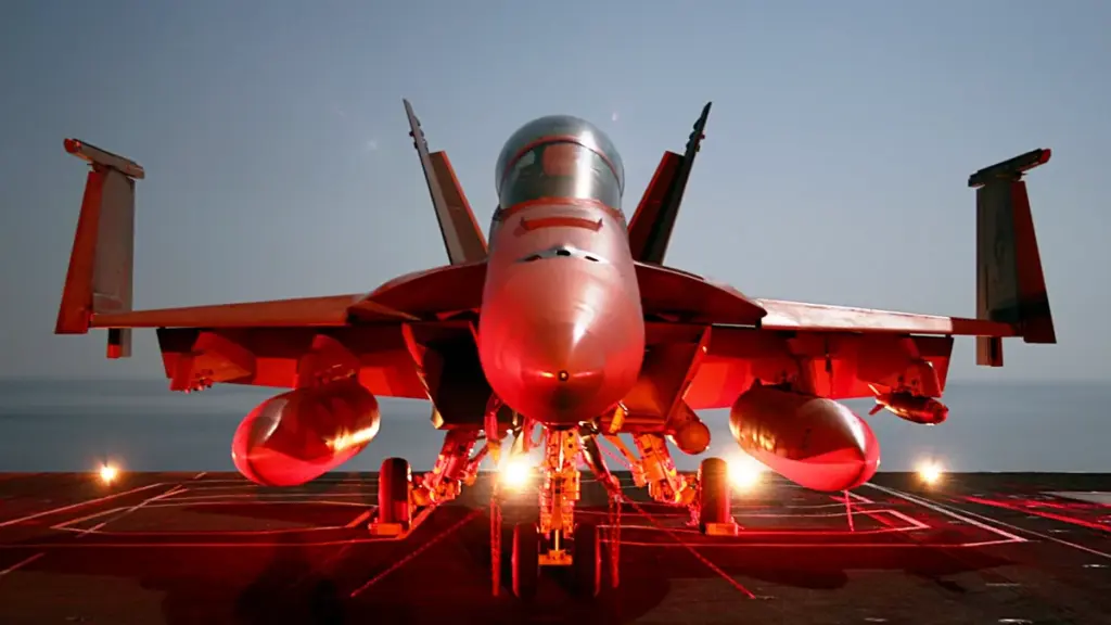 Photograph of a naval F/A-18 Super Hornet combat aircraft chained securely to the flight deck of a deployed U.S. Navy aircraft carrier at sea.