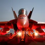 Photograph of a naval F/A-18 Super Hornet combat aircraft chained securely to the flight deck of a deployed U.S. Navy aircraft carrier at sea.