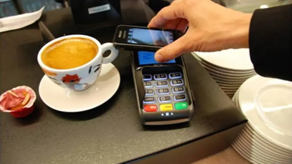 Close-up photograph of a user holding a smartphone during a digital payment transaction.
