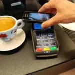 Close-up photograph of a user holding a smartphone during a digital payment transaction.