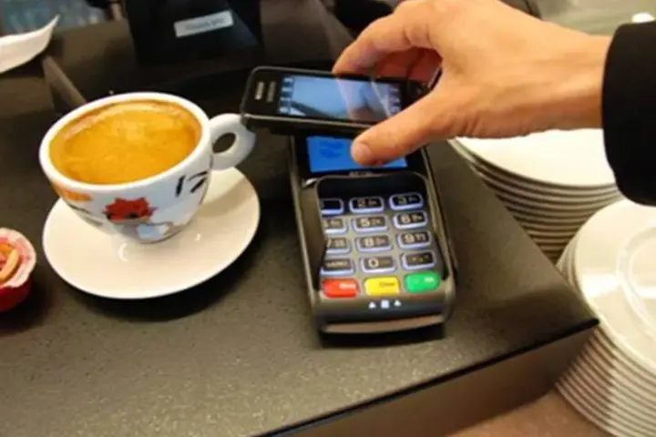 Close-up photograph of a user holding a smartphone during a digital payment transaction.