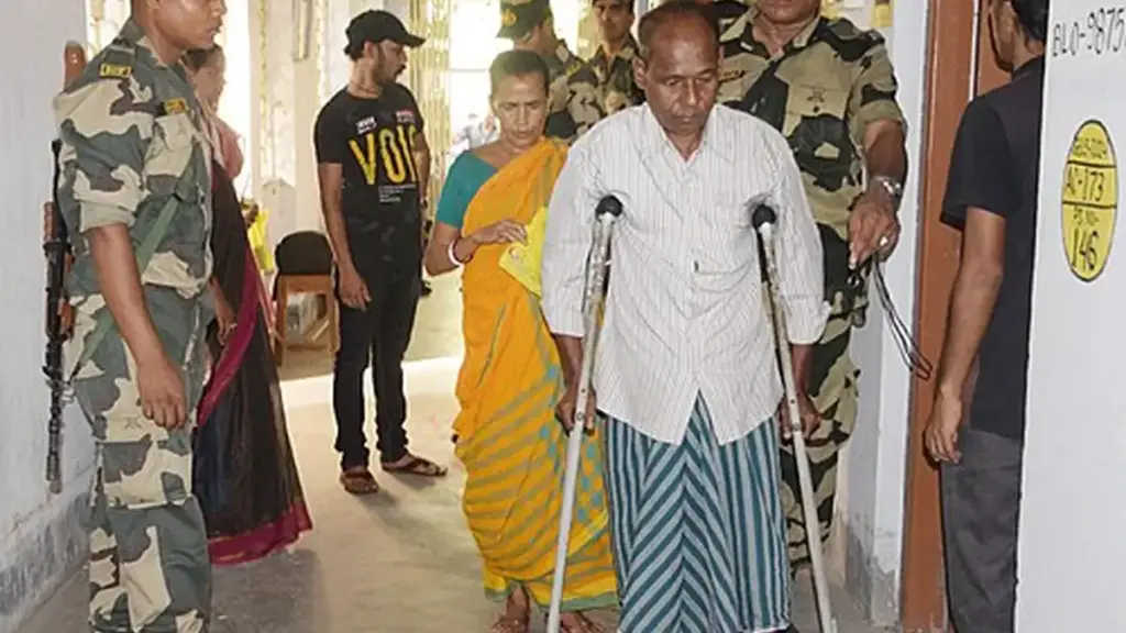 Security personnel assisting a voter at a polling booth in West Bengal during India’s 2024 general election.