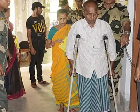 Security personnel assisting a voter at a polling booth in West Bengal during India’s 2024 general election.