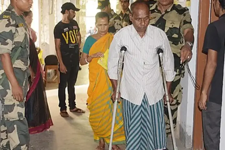 Security personnel assisting a voter at a polling booth in West Bengal during India’s 2024 general election.
